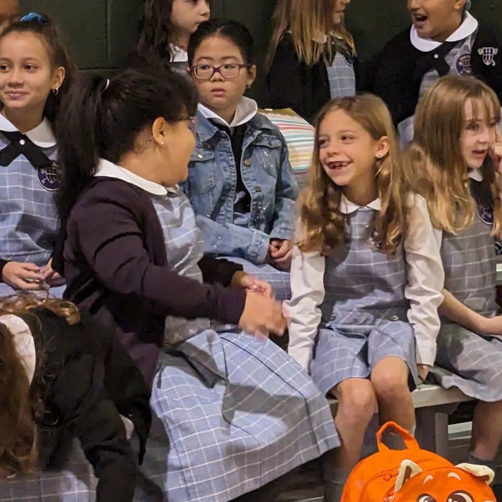 Third grade students in Catholic School uniforms talking and laughing with each other.